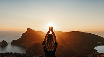 listing-womens-hands-held-above-head-over-sun-setting-over-an-island-and-sea-background.jpg